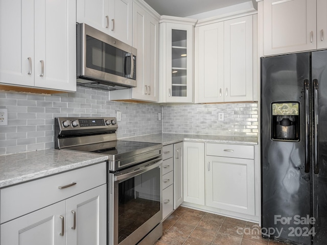 kitchen with white cabinets, decorative backsplash, stainless steel appliances, and light stone countertops