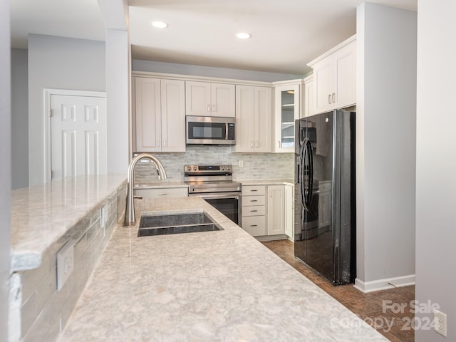 kitchen with white cabinets, sink, dark tile patterned floors, appliances with stainless steel finishes, and tasteful backsplash