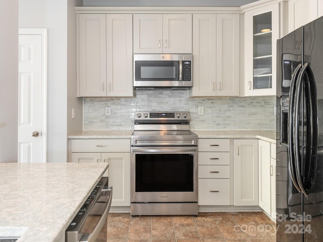 kitchen with white cabinets, tasteful backsplash, light stone countertops, and black appliances