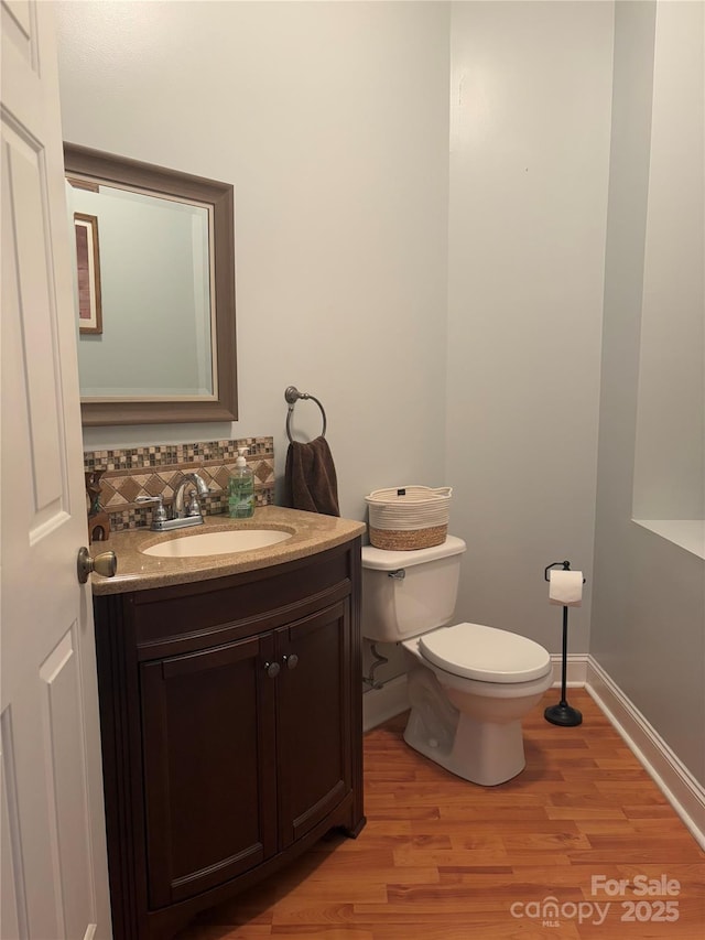 bathroom with hardwood / wood-style floors, toilet, decorative backsplash, and vanity