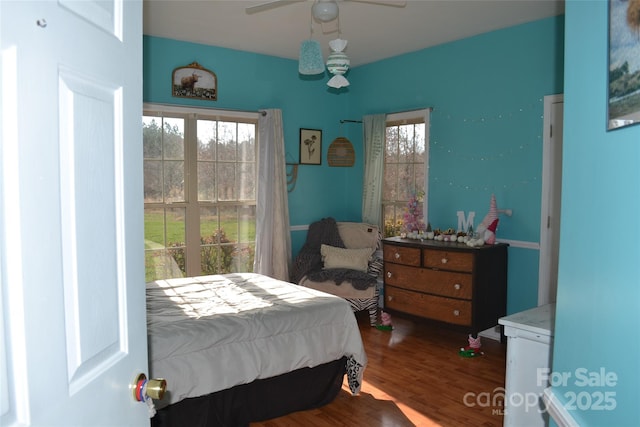 bedroom featuring ceiling fan, wood-type flooring, and multiple windows