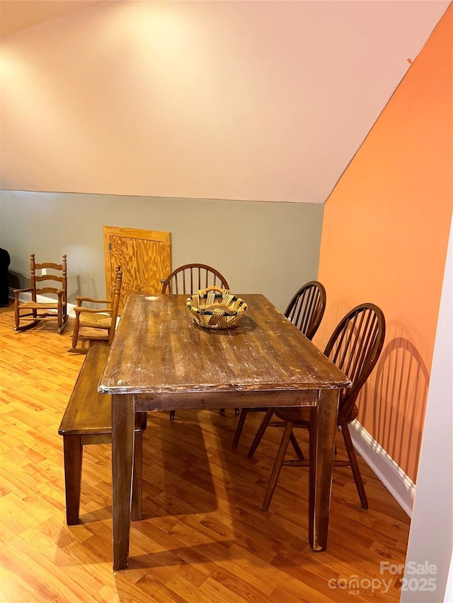 dining area with light wood-type flooring and lofted ceiling