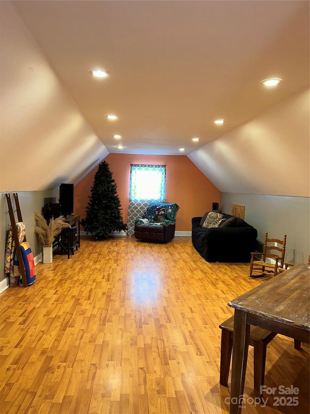 additional living space with vaulted ceiling and light hardwood / wood-style flooring