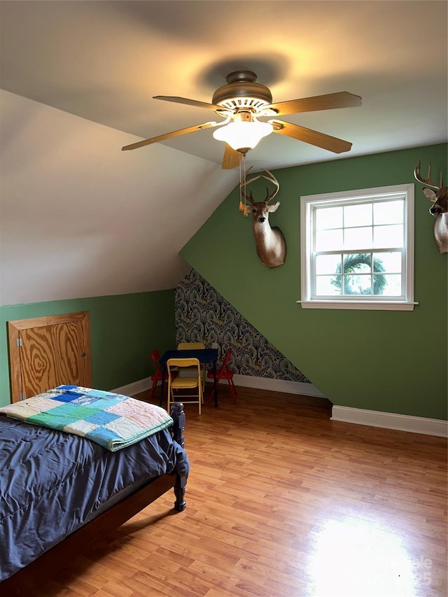 bedroom with ceiling fan, light hardwood / wood-style floors, and vaulted ceiling