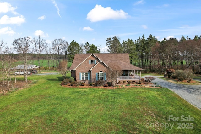 view of front of property with brick siding, a porch, driveway, and a front yard