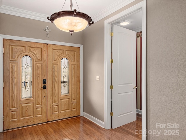 entryway featuring light wood-type flooring, baseboards, and ornamental molding