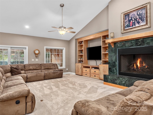 living room featuring carpet flooring, a premium fireplace, baseboards, ceiling fan, and vaulted ceiling