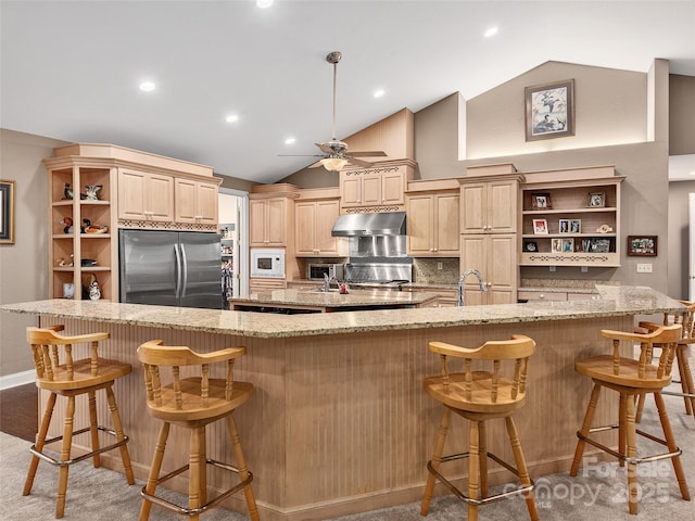 kitchen with under cabinet range hood, stainless steel refrigerator, white microwave, and open shelves