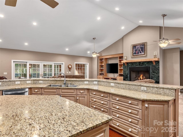 kitchen featuring a sink, light stone counters, dishwasher, and open floor plan