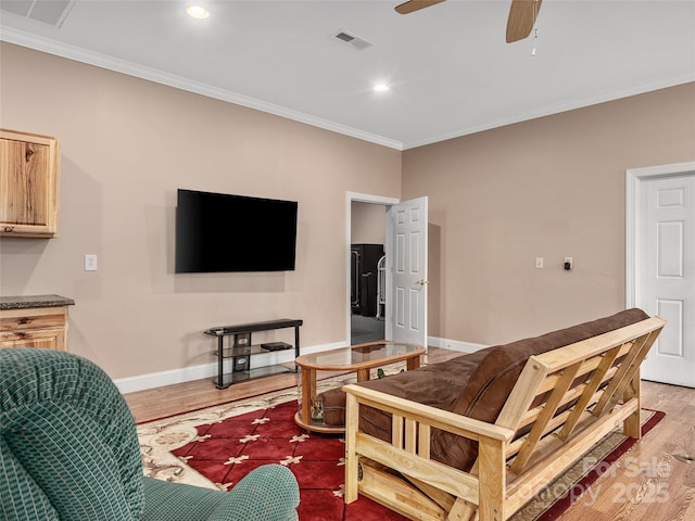 living area featuring visible vents, a ceiling fan, crown molding, light wood finished floors, and baseboards