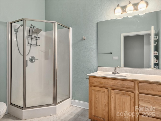 full bath featuring toilet, a stall shower, vanity, and a textured wall