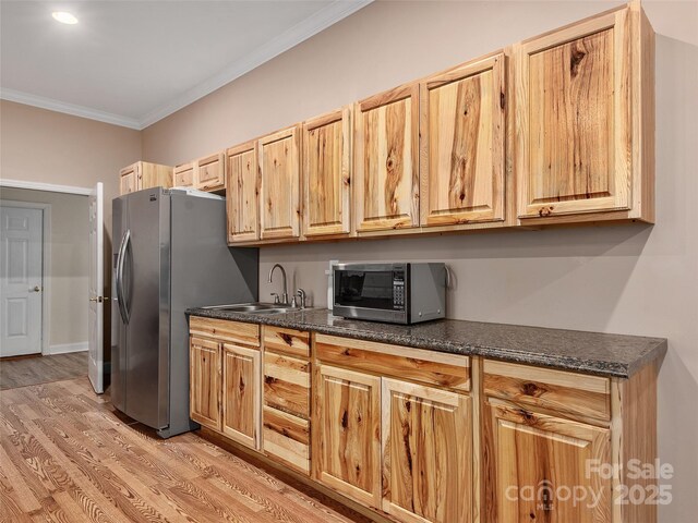 kitchen featuring dark countertops, appliances with stainless steel finishes, crown molding, and a sink