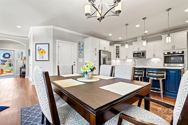 dining room with hardwood / wood-style flooring, crown molding, and a notable chandelier