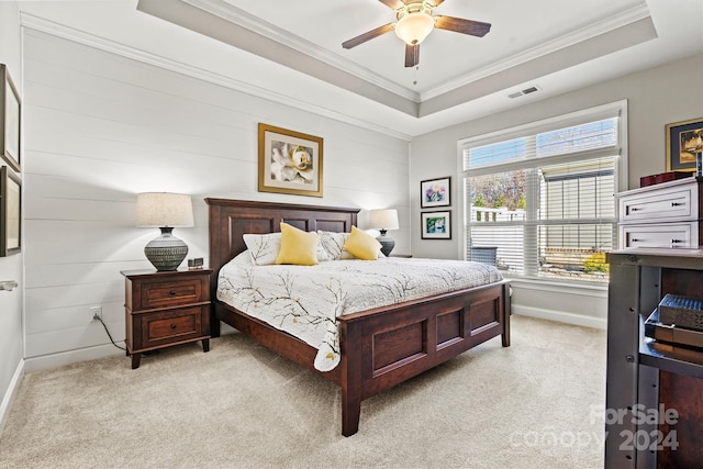 carpeted bedroom with a tray ceiling, ceiling fan, and ornamental molding