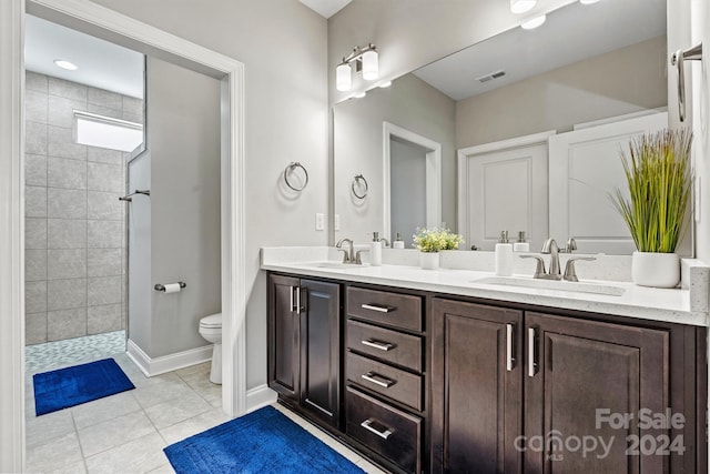 bathroom featuring tile patterned floors, vanity, tiled shower, and toilet