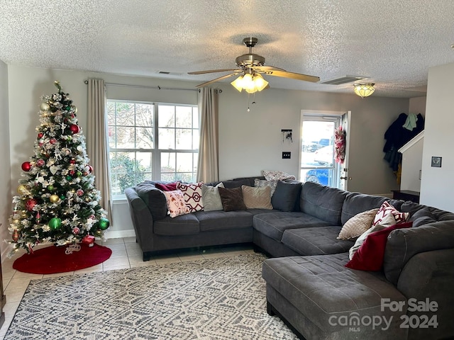 living room with ceiling fan, light tile patterned flooring, and a textured ceiling