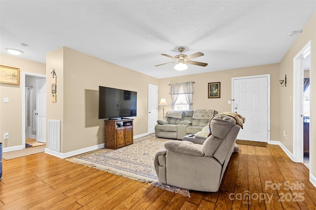 living room featuring hardwood / wood-style flooring, ceiling fan, and a textured ceiling