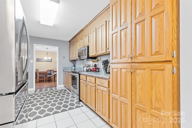 kitchen featuring appliances with stainless steel finishes, a textured ceiling, light tile patterned floors, pendant lighting, and an inviting chandelier