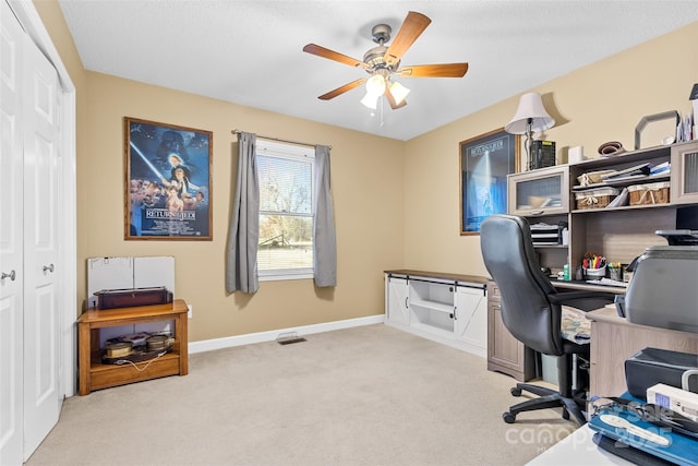 home office featuring light carpet, ceiling fan, and a textured ceiling