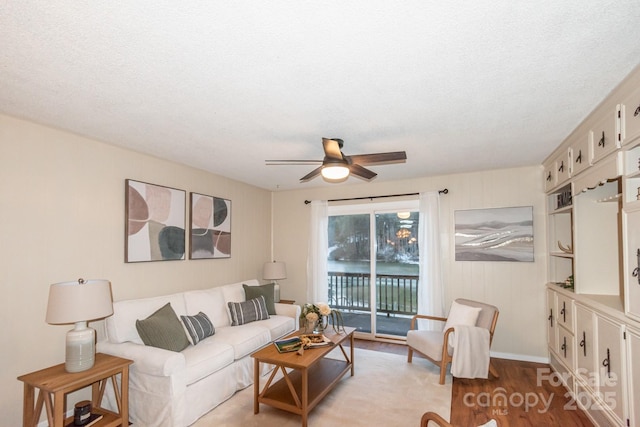 living room featuring ceiling fan, a textured ceiling, and light hardwood / wood-style flooring