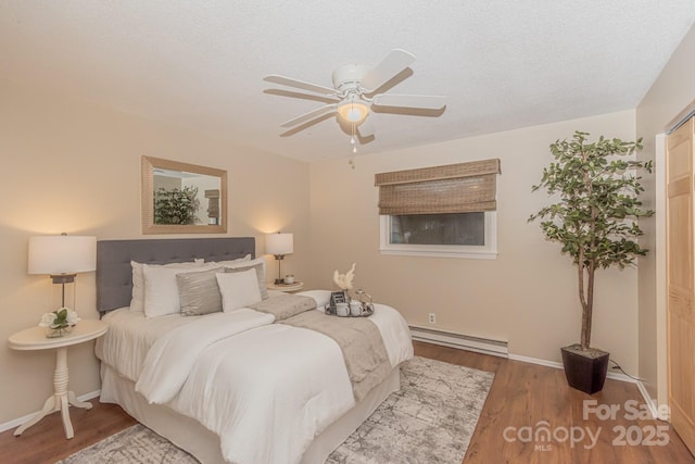 bedroom with baseboard heating, ceiling fan, a textured ceiling, and hardwood / wood-style flooring