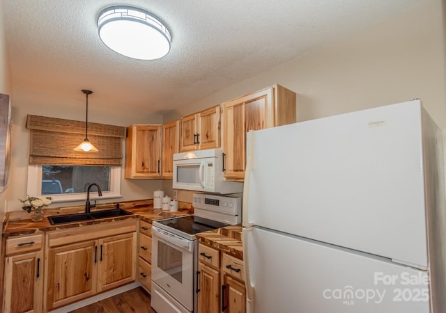 kitchen featuring dark hardwood / wood-style flooring, a textured ceiling, white appliances, sink, and hanging light fixtures