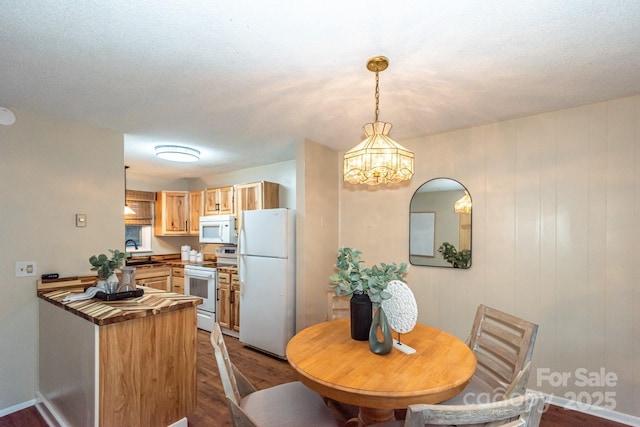 dining space with wood-type flooring, a textured ceiling, an inviting chandelier, and sink