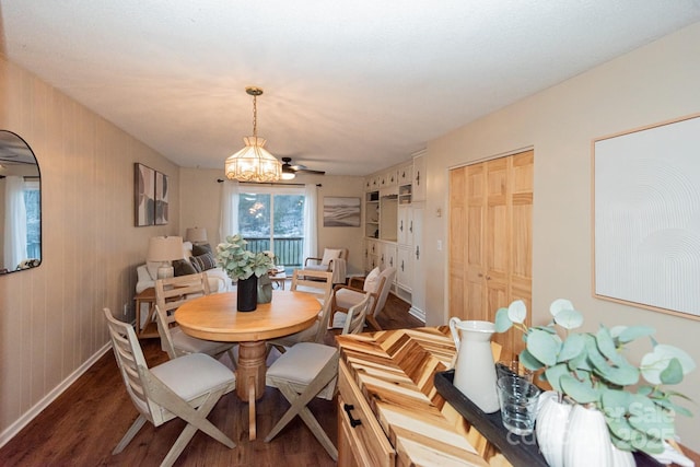 dining room with ceiling fan with notable chandelier and dark wood-type flooring