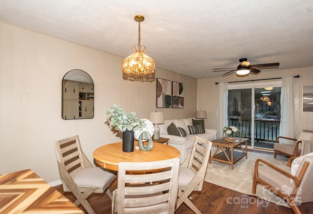 dining room with hardwood / wood-style floors, ceiling fan with notable chandelier, and a textured ceiling