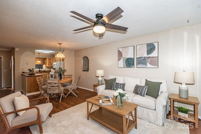 living room with sink, ceiling fan with notable chandelier, light hardwood / wood-style floors, and a textured ceiling