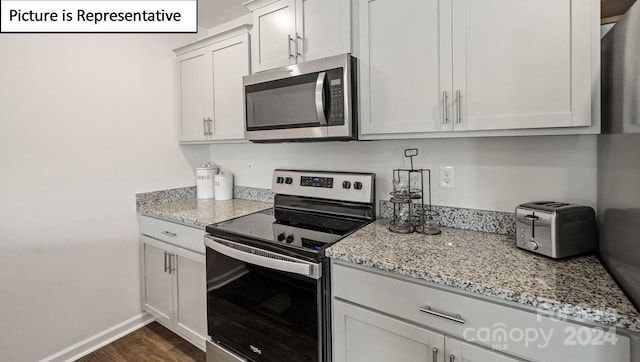 kitchen with white cabinets, stainless steel appliances, light stone countertops, and dark wood-type flooring