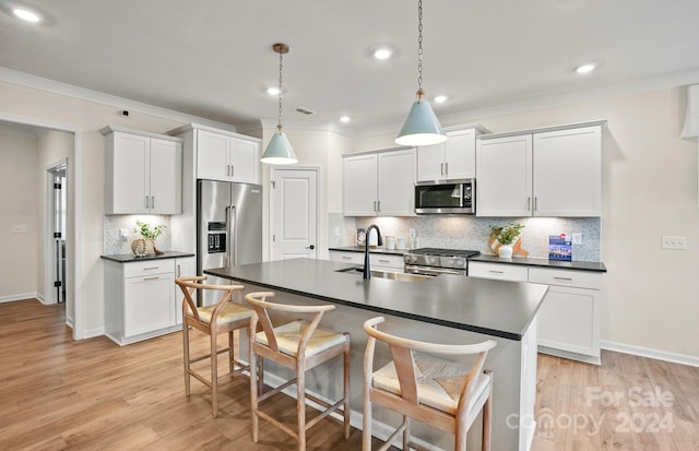 kitchen featuring a breakfast bar, high quality appliances, sink, light wood-type flooring, and decorative light fixtures