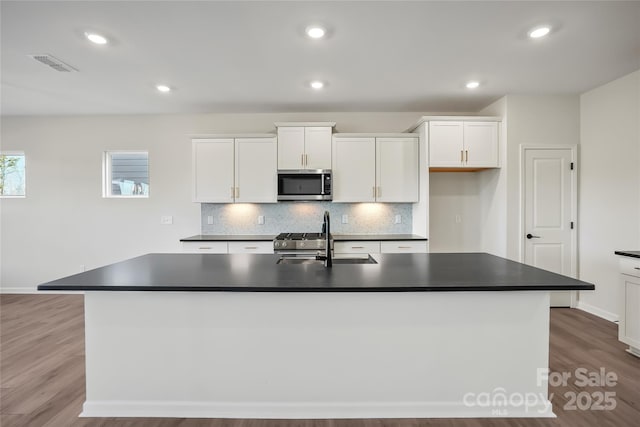 kitchen featuring white cabinetry, a center island with sink, stainless steel appliances, sink, and tasteful backsplash