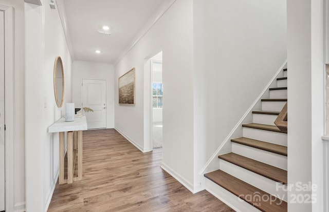 hallway featuring light wood-type flooring and ornamental molding