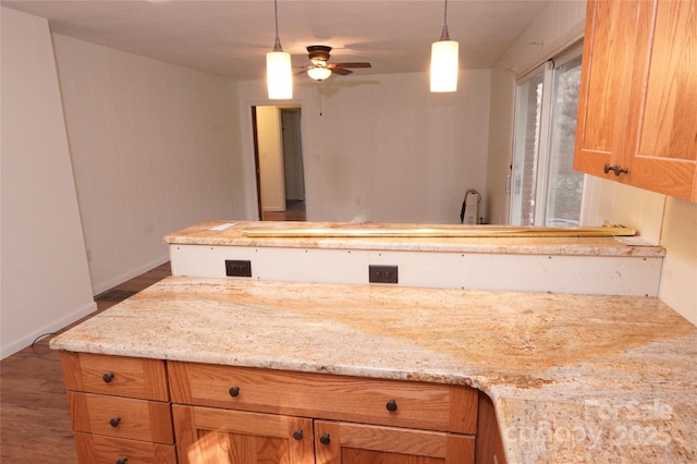 kitchen featuring ceiling fan, light stone counters, dark wood-type flooring, and decorative light fixtures