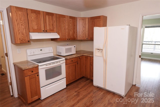 kitchen with under cabinet range hood, white appliances, brown cabinetry, and wood finished floors