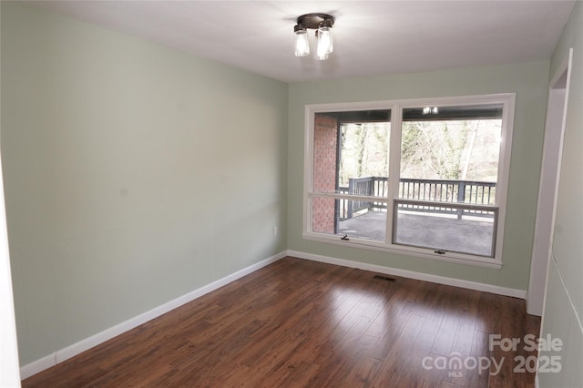 unfurnished room with visible vents, baseboards, and dark wood finished floors