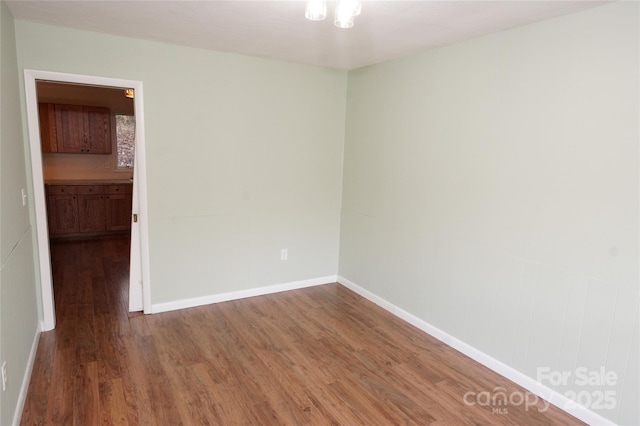 unfurnished room featuring baseboards and wood finished floors