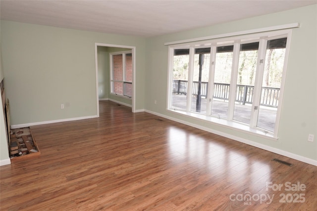empty room with visible vents, baseboards, and wood finished floors