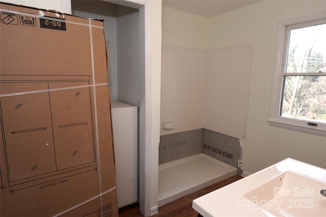 bathroom with a sink, tiled shower, and wood finished floors