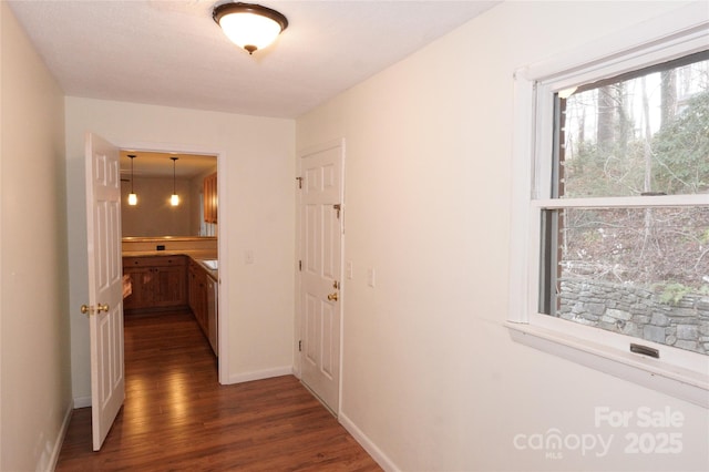 corridor with dark wood-type flooring and baseboards