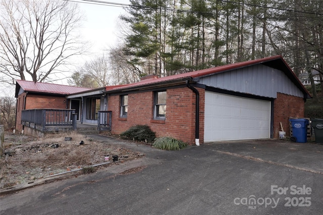 ranch-style house with brick siding, metal roof, and driveway