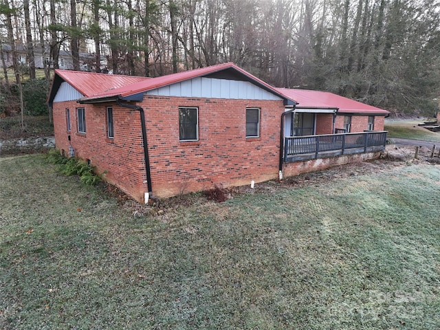 view of home's exterior featuring brick siding, metal roof, and a lawn
