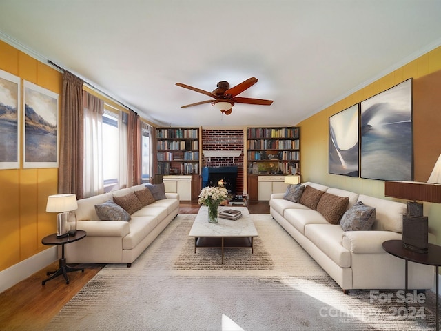 living room with crown molding, hardwood / wood-style floors, ceiling fan, and a brick fireplace