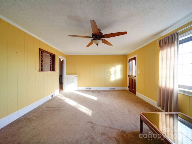 carpeted empty room with a textured ceiling, ceiling fan, and ornamental molding