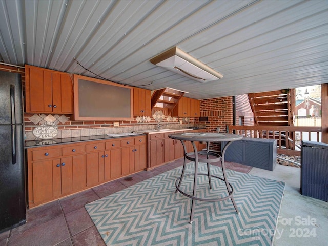 kitchen featuring black refrigerator, tasteful backsplash, and sink