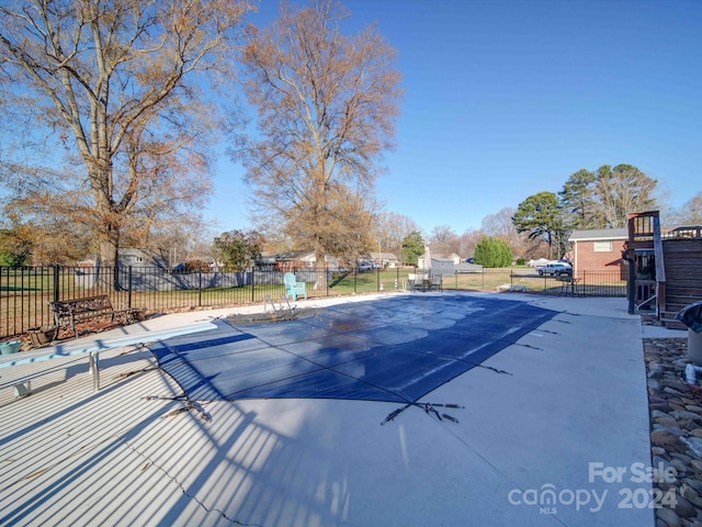 view of swimming pool with a diving board and a patio area