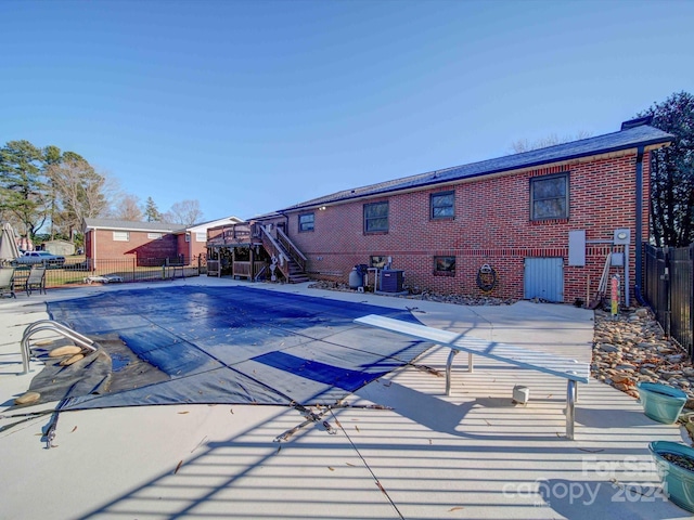 view of swimming pool with a diving board, a patio area, and central AC