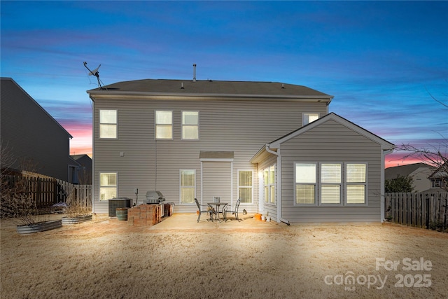 back house at dusk with central AC unit and a patio area