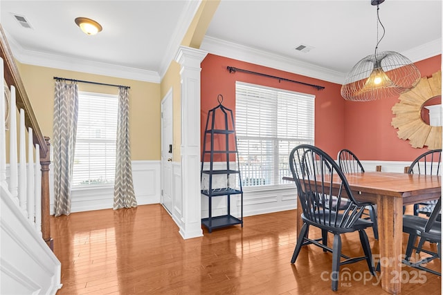 dining room with a wealth of natural light, crown molding, and hardwood / wood-style flooring